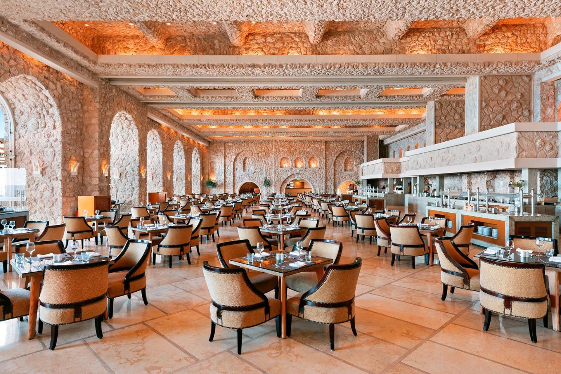 Pickalbatros Citadel Resort Sahl Hasheesh (Adults Only) Hurghada Exterior foto The photo shows an elegant restaurant interior characterized by a spacious layout. The dining area features numerous tables set with fine dining arrangements. Stylish chairs surround the tables, and the overall decor includes stone walls and archway 